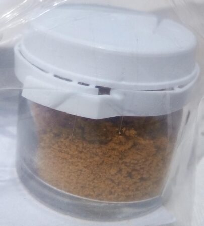 Vue en gros plan d'un monticule ou d'un petit pot de propolis en poudre Miel et Délices, montrant sa texture fine et sa couleur brun-doré. Cette forme de propolis est facile à mélanger et riche en principes actifs.