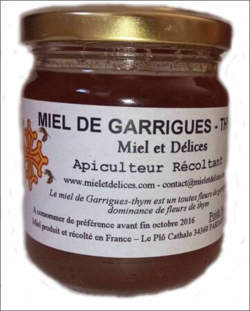 Pot de miel de garrigues au thym Miel et Délices, montrant sa couleur ambrée et sa texture dense. Ce miel puissant et aromatique offre un goût herbacé intense, récolté artisanalement au cœur de la garrigue de l'Hérault.